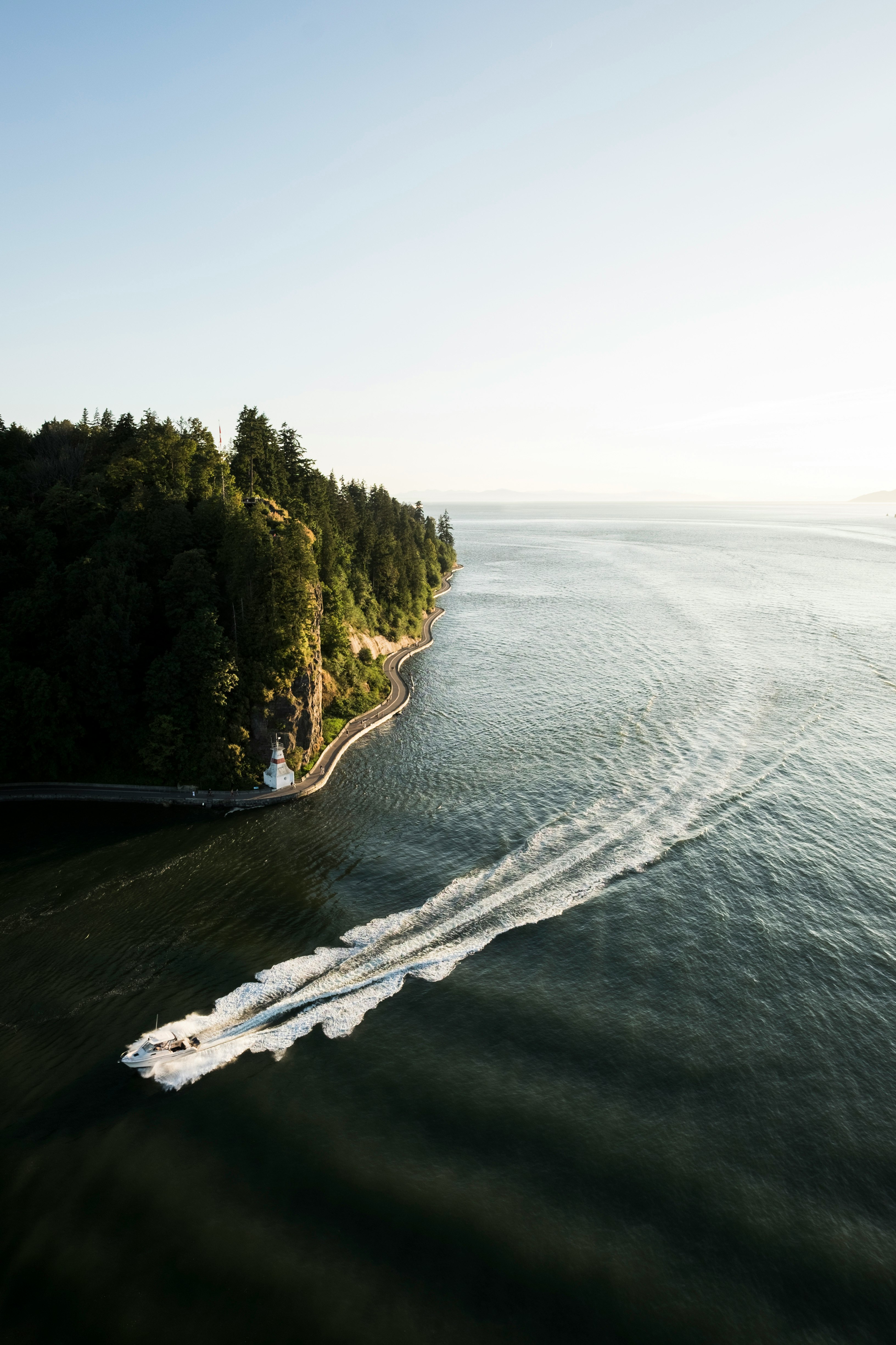 white speedboat passing on sea under clear blue sky during daytime